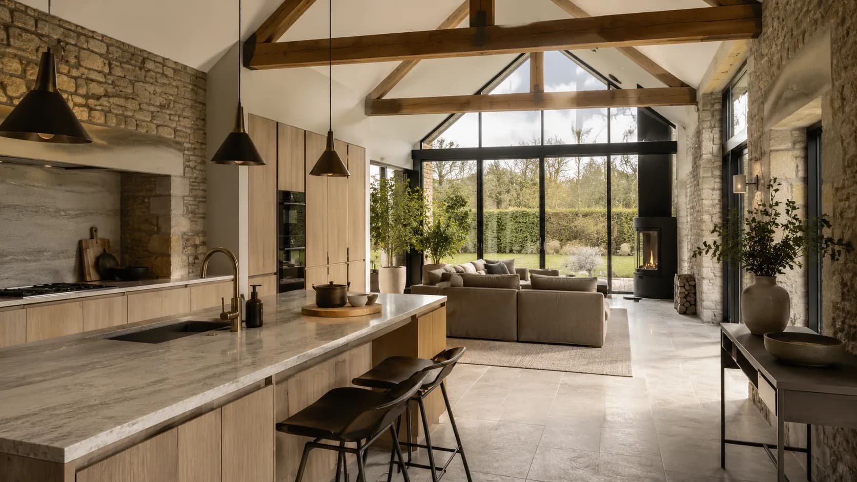 SPEC sample interior visual of a premium UK barn-style open-plan kitchen and living space with natural stone, oak, honed worktop, and black steel glazing in soft daylight.
